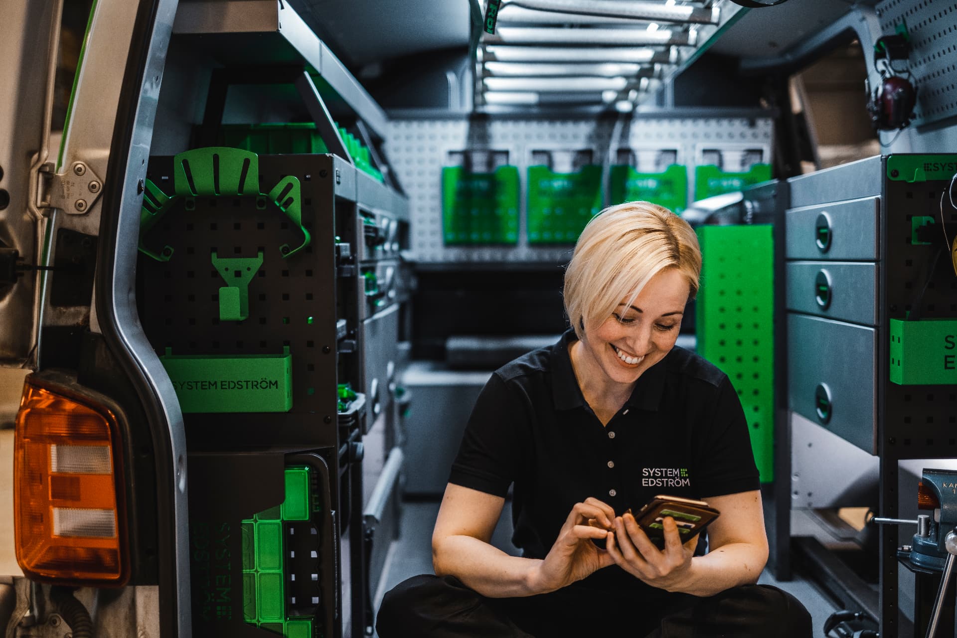 Servicetechnikerin arbeitet im ausgebauten Transporter am Tablet
