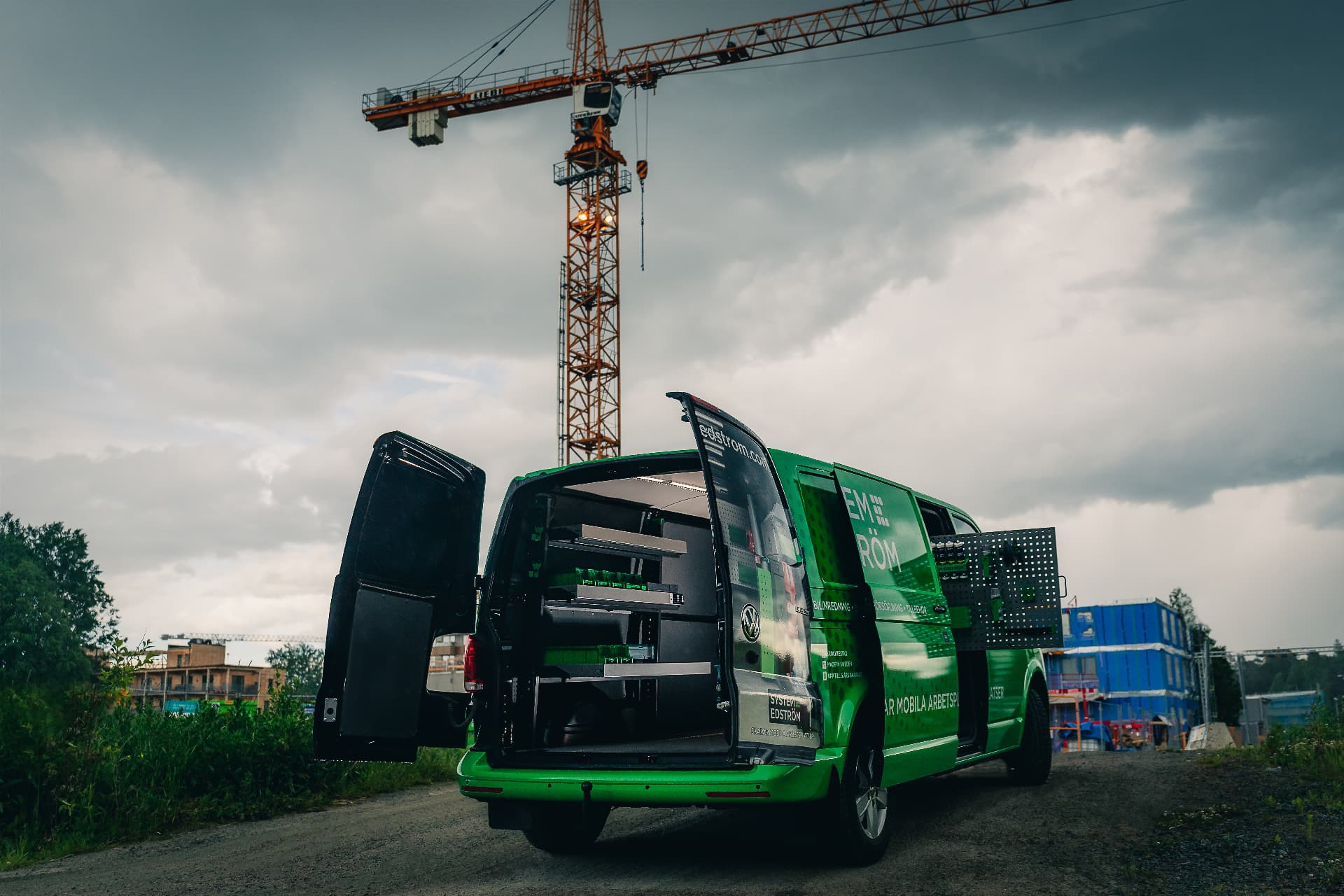 Grüner VW Transporter mit offenen Hecktüren vor einem Baukran