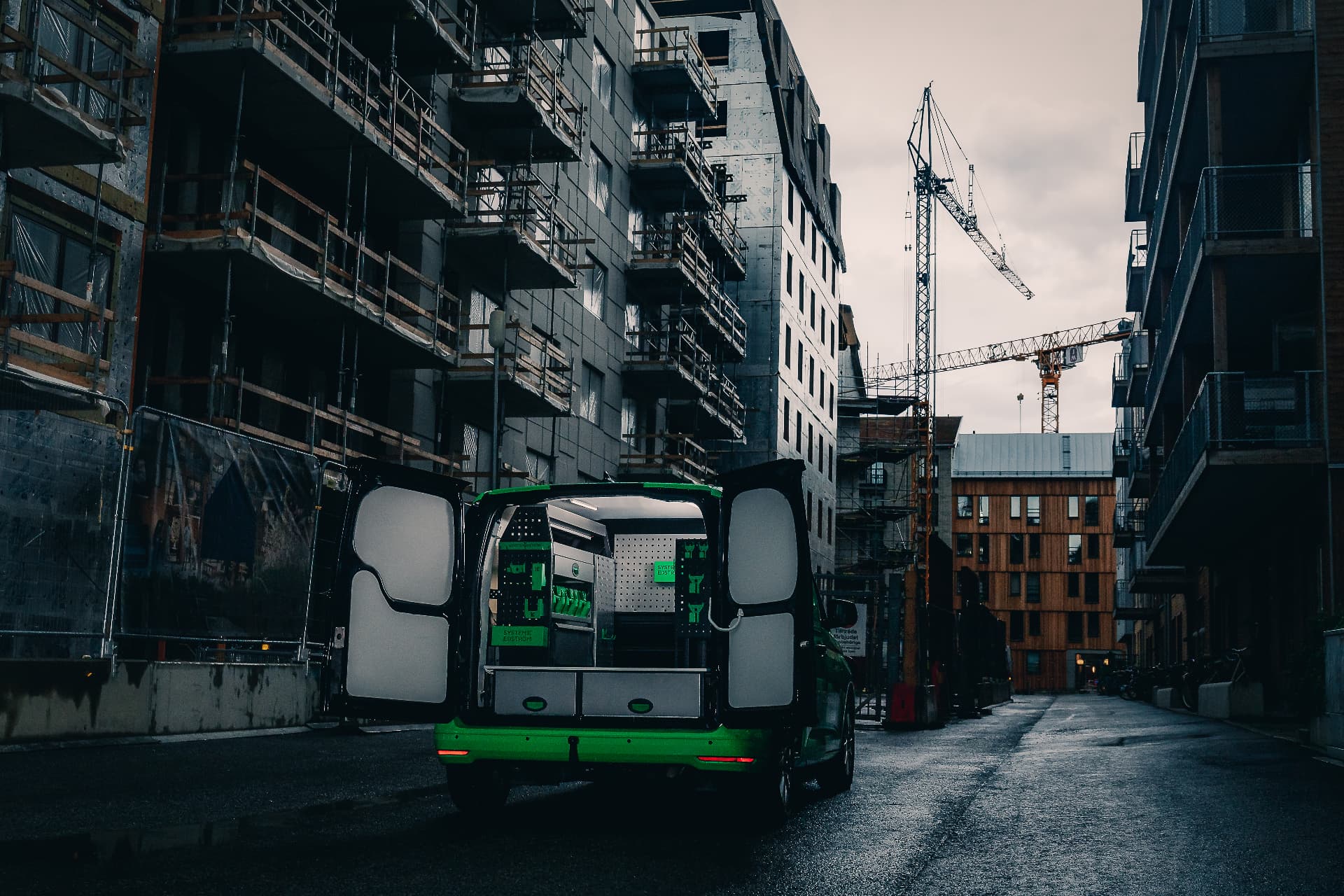 Transporter mit offenen Hecktüren zwischen städtischen Neubauten